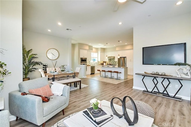 living area with light wood-type flooring, recessed lighting, ceiling fan, and visible vents