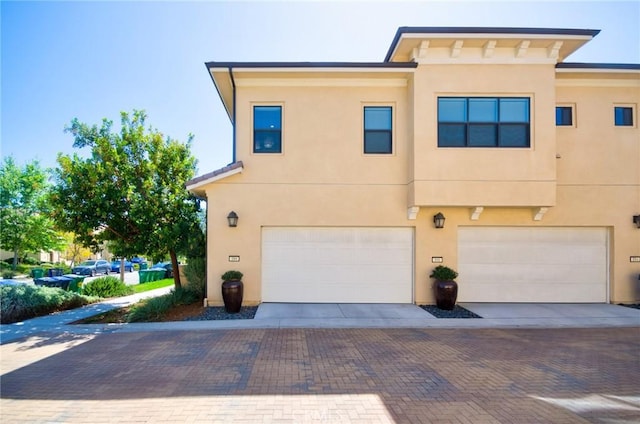 view of front of home with decorative driveway, a garage, and stucco siding