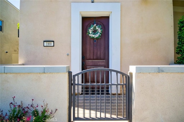 entrance to property featuring a gate and stucco siding