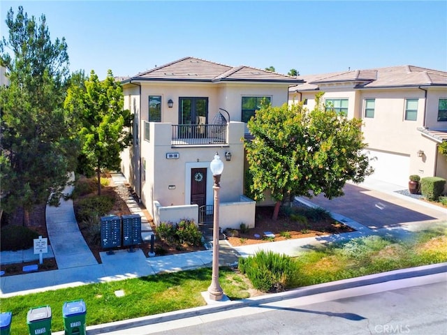 view of property featuring stucco siding, a balcony, and a tile roof