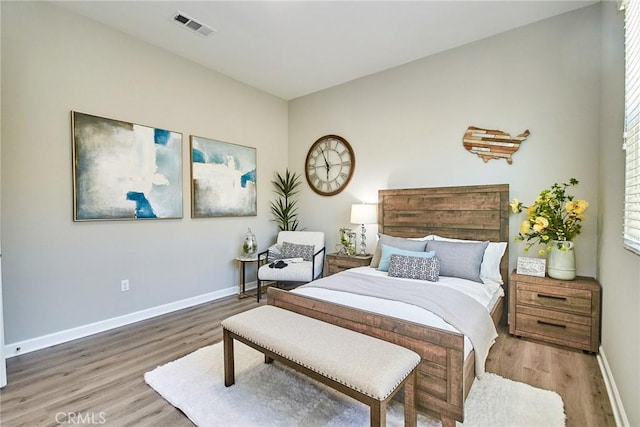 bedroom with baseboards, visible vents, and wood finished floors