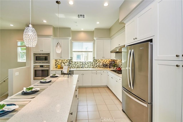 kitchen featuring appliances with stainless steel finishes, plenty of natural light, under cabinet range hood, and white cabinetry
