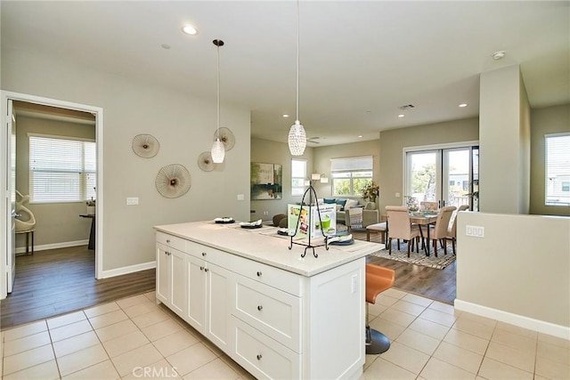 kitchen featuring light tile patterned floors, light countertops, white cabinets, and a kitchen island