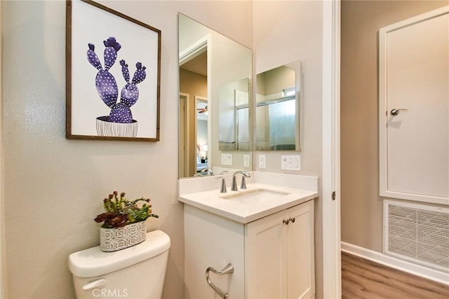 bathroom featuring visible vents, wood finished floors, vanity, baseboards, and toilet
