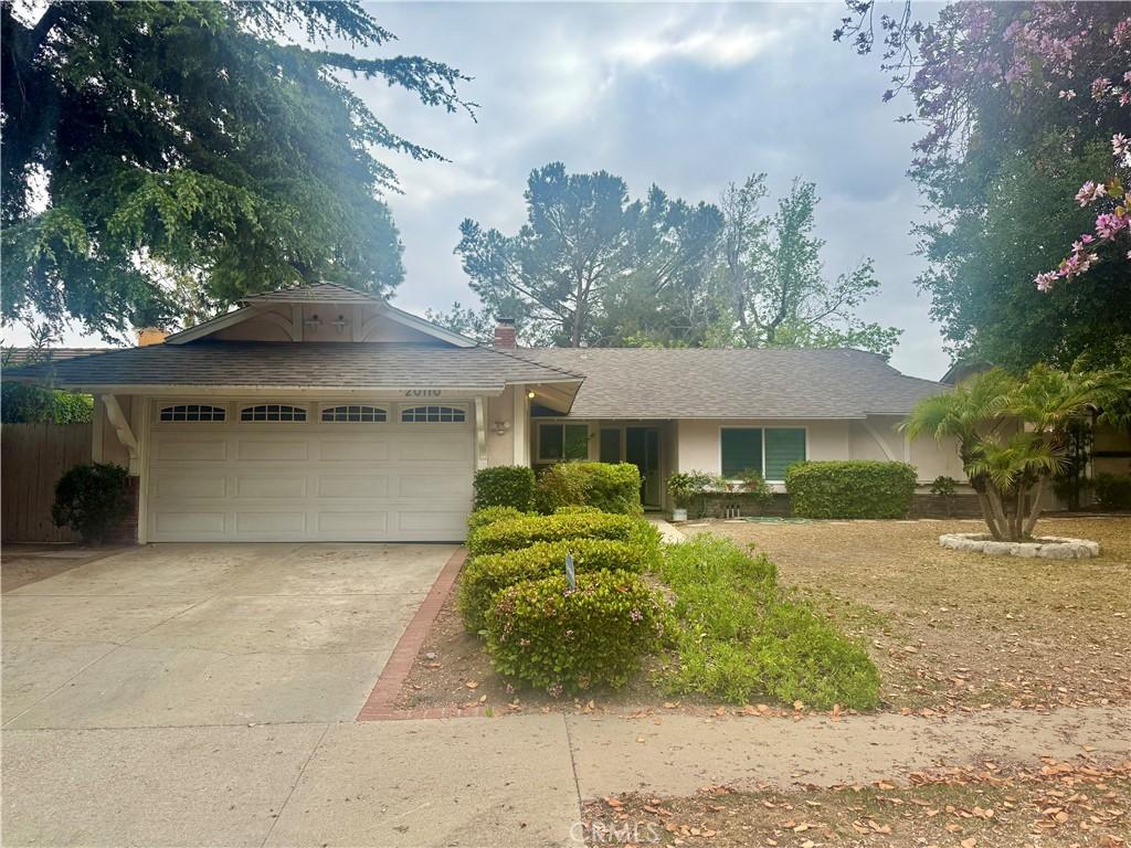 ranch-style house with a garage, stucco siding, and driveway