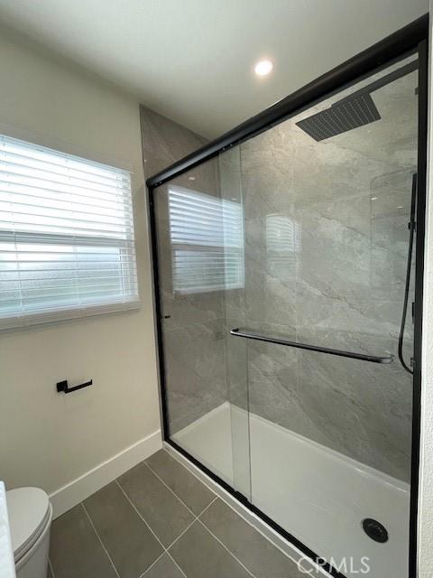 full bathroom with baseboards, tile patterned flooring, a shower stall, and toilet