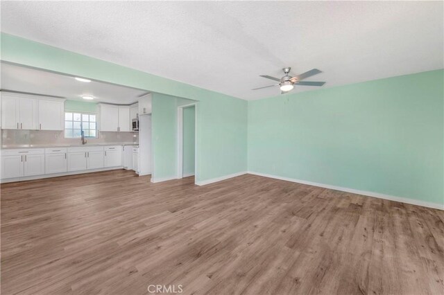 3882 Dwiggins St, Los Angeles, CA 90063 - unfurnished living room with ceiling fan, light wood-style floors, baseboards, and a sink