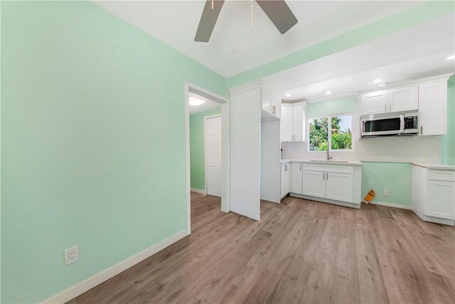 3882 Dwiggins St, Los Angeles, CA 90063 - kitchen featuring stainless steel microwave, ceiling fan, light wood-type flooring, white cabinets, and baseboards