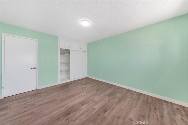 3882 Dwiggins St, Los Angeles, CA 90063 - unfurnished bedroom with wood finished floors, a closet, baseboards, and a textured ceiling