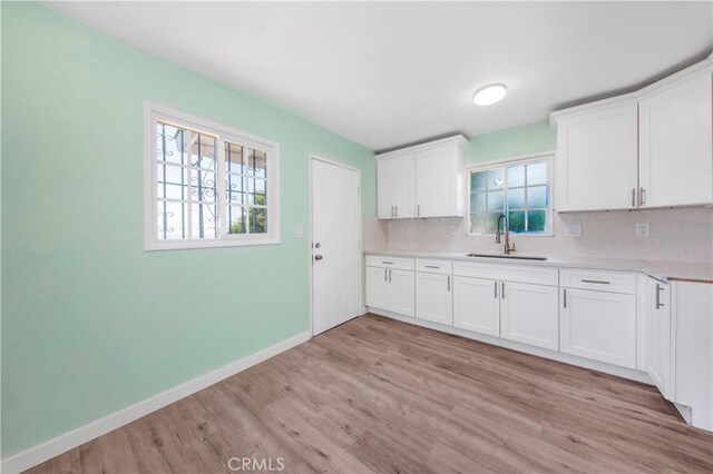 3882 Dwiggins St, Los Angeles, CA 90063 - kitchen with a sink, light wood-style floors, light countertops, white cabinetry, and baseboards