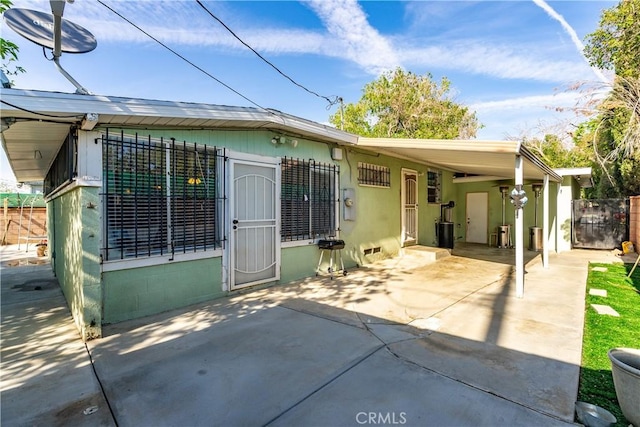 rear view of house featuring a patio area, fence, driveway, and an attached carport
