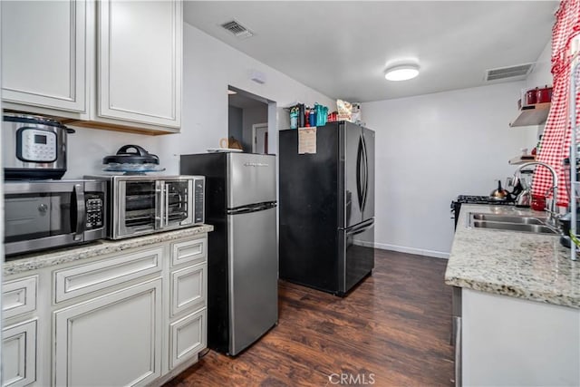 kitchen with a sink, appliances with stainless steel finishes, dark wood-style floors, and visible vents