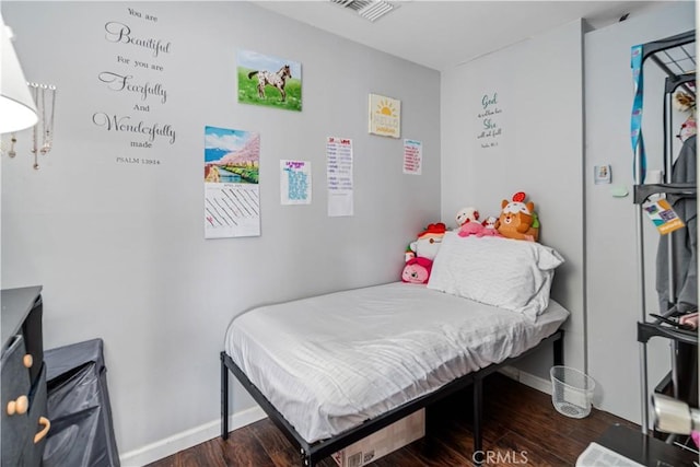 bedroom with baseboards, wood finished floors, and visible vents