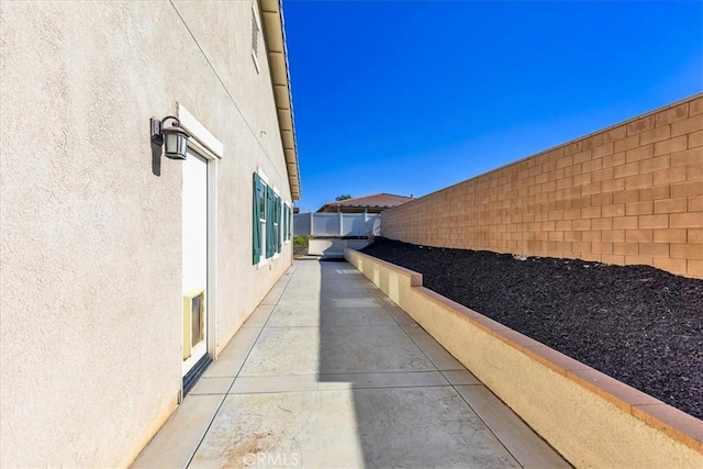 view of side of property featuring fence and stucco siding