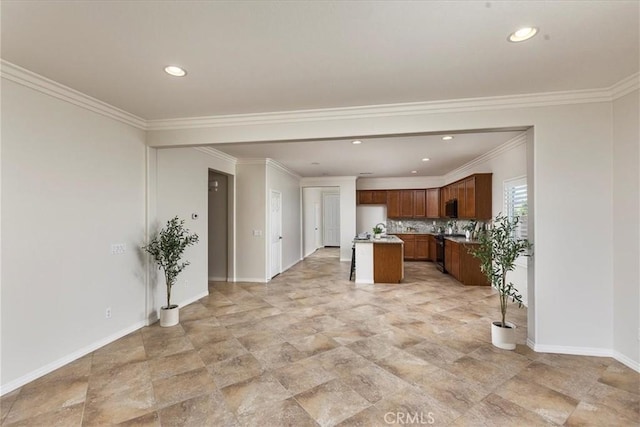 kitchen featuring baseboards, ornamental molding, a kitchen island, and recessed lighting