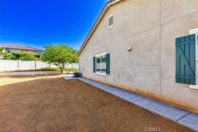 view of home's exterior featuring central air condition unit, fence, and stucco siding