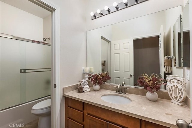 bathroom with vanity, bath / shower combo with glass door, and toilet