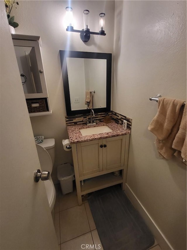 bathroom with tile patterned flooring, baseboards, toilet, and vanity