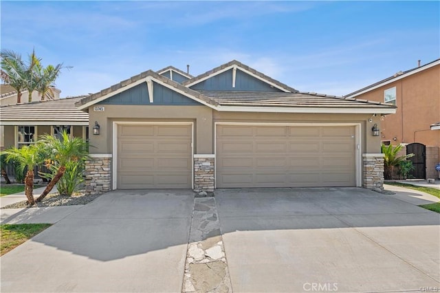 view of front of house with an attached garage, a tile roof, driveway, and stone siding