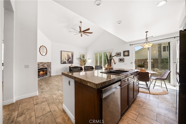 kitchen with dark brown cabinetry, a ceiling fan, a fireplace, a sink, and stainless steel appliances