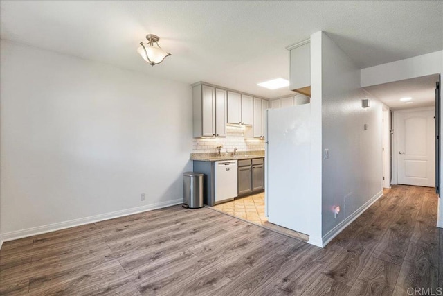 kitchen with light wood-style floors, decorative backsplash, white appliances, and light countertops