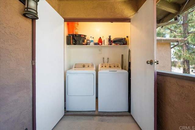 laundry area featuring a textured wall, laundry area, and washer and clothes dryer