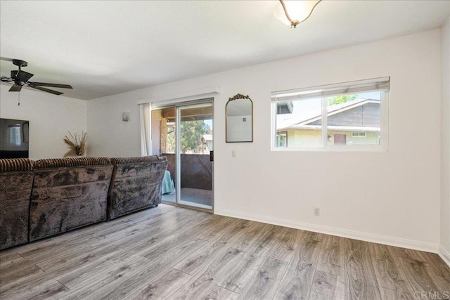 unfurnished living room with baseboards, a ceiling fan, and light wood-type flooring