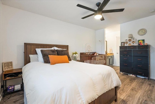 bedroom with connected bathroom, ceiling fan, and wood finished floors