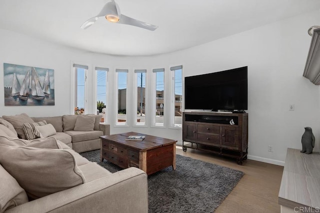 living area with baseboards, a ceiling fan, and wood finished floors