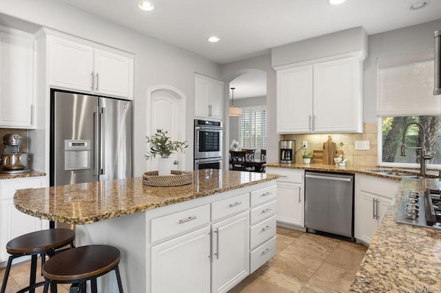 kitchen with a sink, a kitchen breakfast bar, stainless steel appliances, recessed lighting, and decorative backsplash