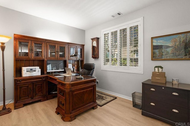 home office with baseboards, light wood-style flooring, and visible vents