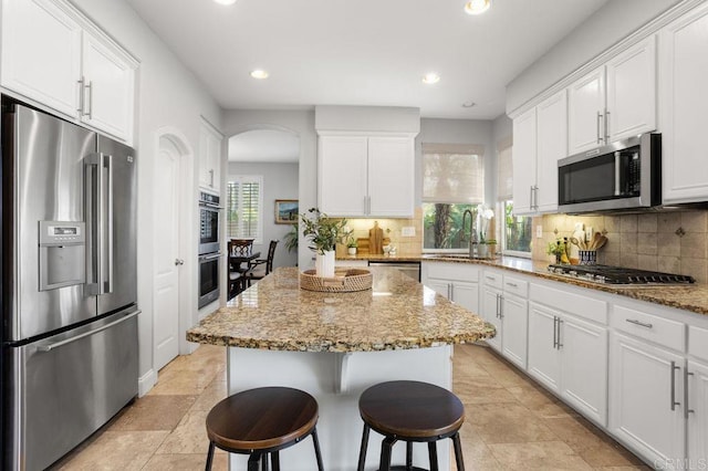 kitchen with a sink, stainless steel appliances, white cabinetry, and a healthy amount of sunlight