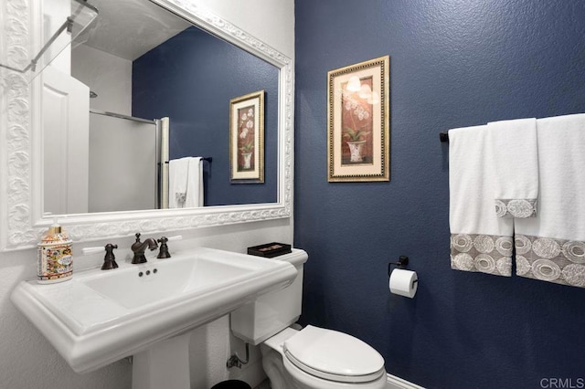 bathroom featuring a textured wall, an enclosed shower, and toilet