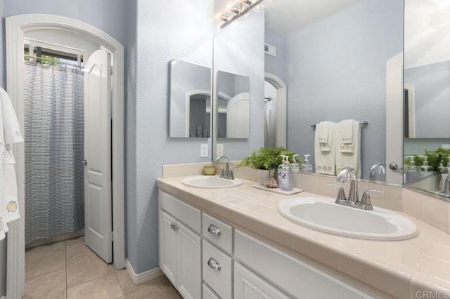 bathroom featuring double vanity, a sink, and tile patterned floors