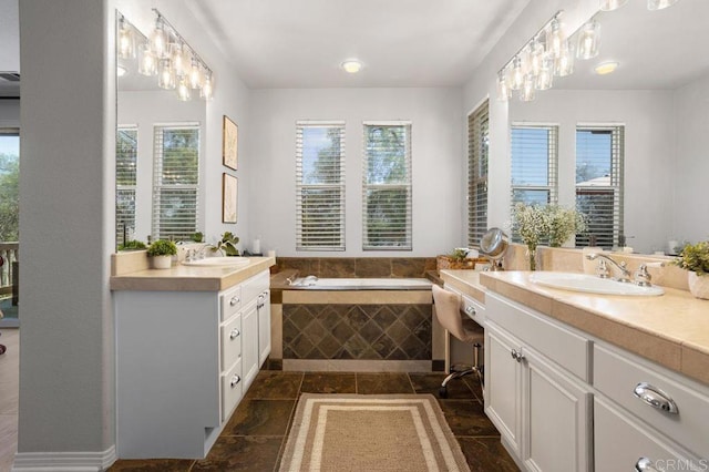 full bath with a sink, a bath, two vanities, and stone finish floor