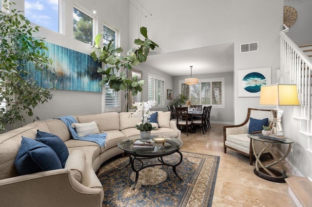 living area featuring visible vents, baseboards, and a high ceiling