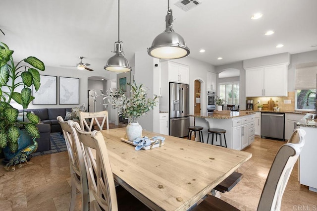 dining room featuring arched walkways, ceiling fan, visible vents, and recessed lighting