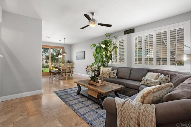 living area featuring baseboards and ceiling fan
