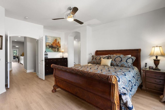 bedroom featuring arched walkways, ceiling fan, and light wood-style flooring