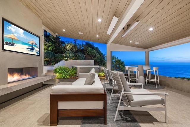 view of patio / terrace featuring a water view and a warm lit fireplace