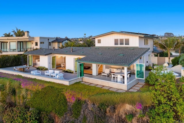 back of property with roof mounted solar panels, outdoor dining space, outdoor lounge area, and a patio