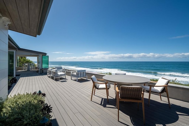 wooden terrace with a water view, a view of the beach, and outdoor dining space