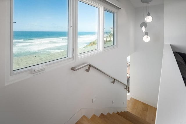 staircase featuring a water view, baseboards, and wood finished floors