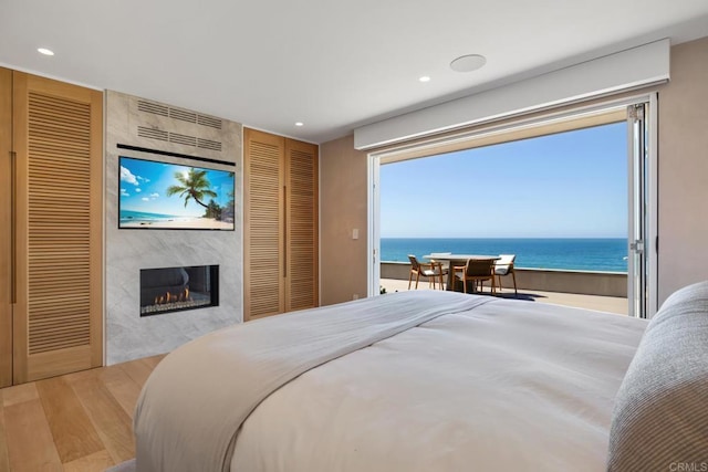 bedroom featuring recessed lighting, wood finished floors, a fireplace, and two closets
