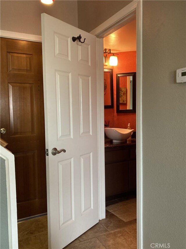 corridor featuring dark tile patterned floors and a sink