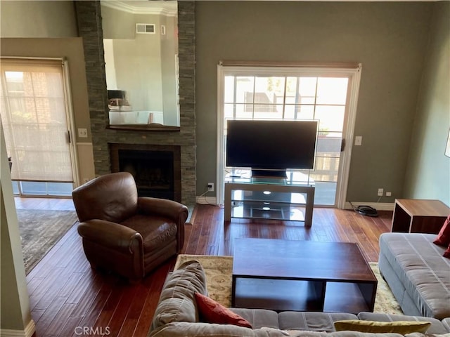 living area with wood-type flooring, baseboards, visible vents, and a large fireplace
