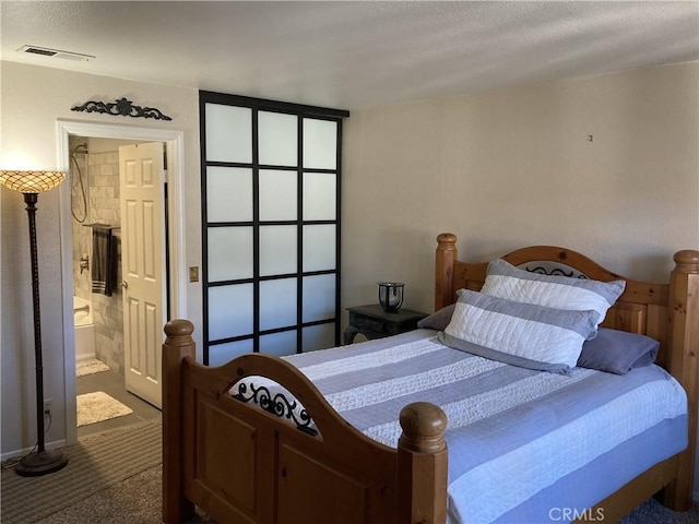 carpeted bedroom featuring visible vents and connected bathroom