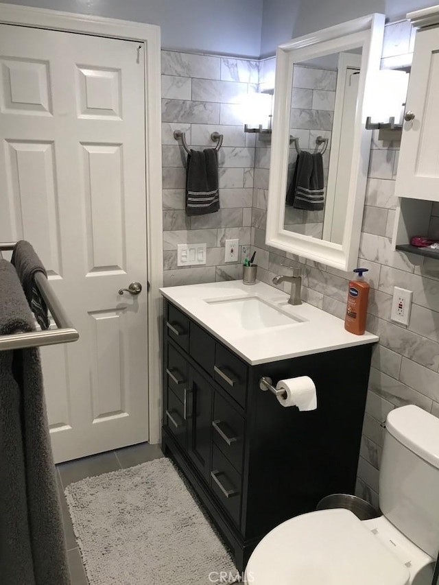 half bath featuring vanity, tile patterned flooring, toilet, and tile walls