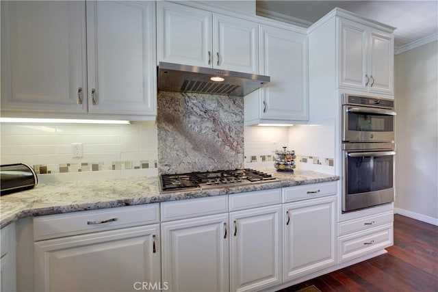 kitchen featuring decorative backsplash, under cabinet range hood, white cabinets, dark wood finished floors, and appliances with stainless steel finishes