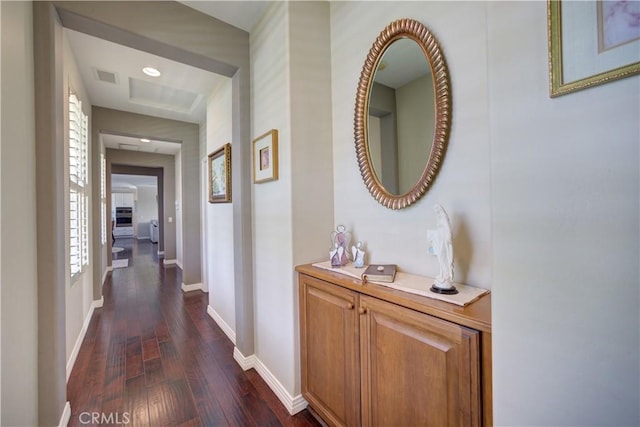 hallway featuring dark wood-style flooring, baseboards, and visible vents